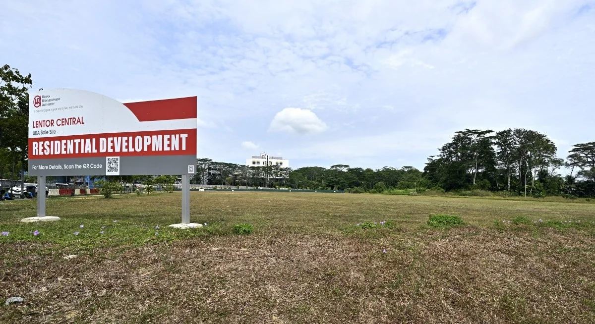 Photograph, illustrative only: the grassed Lentor Central land parcel in Lentor Hills with the URA sale-site board reading Residential Development, and a treeline beyond